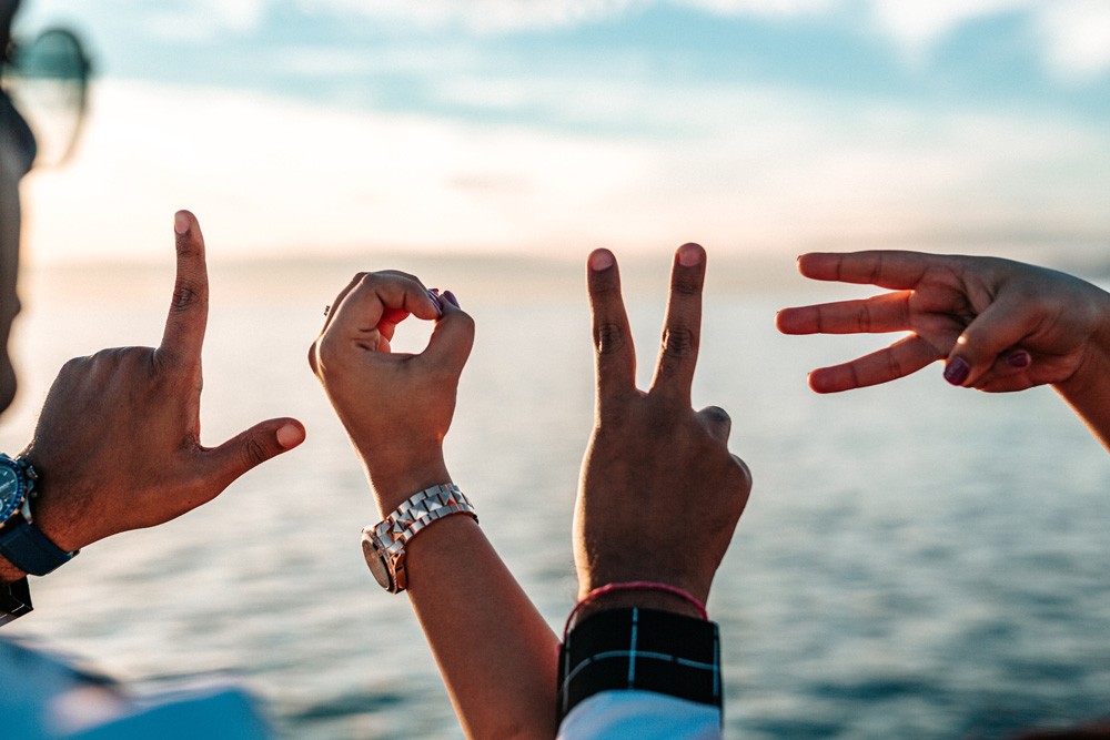 fotografía de unas manos haciendo las letras de "LOVE" y delante el mar